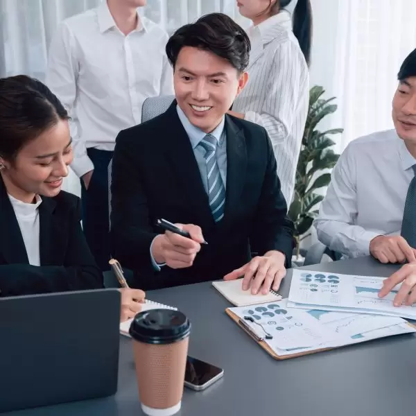 Harmony in office concept as business people analyzing dashboard paper together in workplace. Young colleagues give ideas at manager desk for discussion or strategy planning about project.